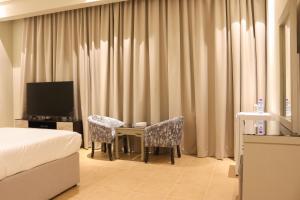 une chambre d'hôtel avec un lit, une table et des chaises dans l'établissement Super OYO Capital O 111 Infinity Suites, à Manama