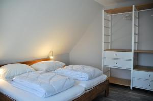 a bed with white sheets and pillows in a room at Burg und Burgstaaken Ferienhaus Viva in Fehmarn