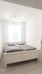 ein weißes Bett in einem Zimmer mit Fenster in der Unterkunft Gemütliche Zweiraumwohnung in Ruhelage in Wien