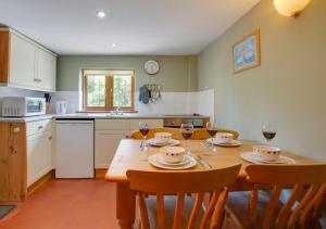 a kitchen with a wooden table with chairs and wine glasses at East Cottage in Corpusty