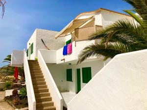 a white building with green doors and a palm tree at Apartamento El Islote direct at Paradise Beach in El Cotillo