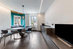 cocina y comedor con mesa y TV en App 205 Palazzo Cavour, en Bolzano