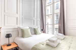 ein weißes Schlafzimmer mit einem großen Bett mit Handtüchern darauf in der Unterkunft Outstanding Parisian flat in heart of Paris center in Paris