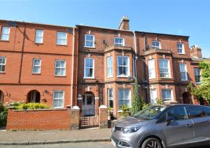 a silver car parked in front of a brick building at Flat 2 in Cromer