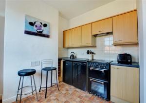 a kitchen with black appliances and two bar stools at Flat 2 in Cromer
