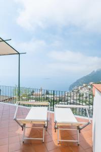 twee witte stoelen op een balkon met uitzicht op de oceaan bij YourHome - Casa Moscatelli 150 steps in Positano