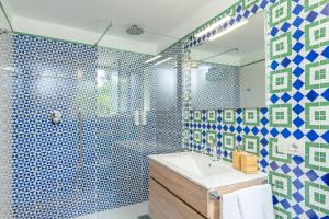 uma casa de banho com um lavatório e um chuveiro com azulejos azuis e verdes em YourHome - Casa Moscatelli 150 steps em Positano