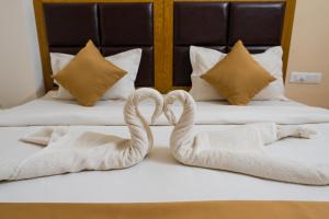 2 asciugamani cigni su un letto in una camera d'albergo di TAG HOTELS a Irugūr