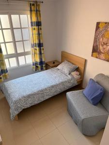 a small bedroom with a bed and a couch at Volcano Beach Views & Wifi in Puerto de Santiago