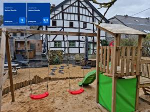 um parque infantil com baloiços em frente a uma casa em Maison Zanella em Durbuy