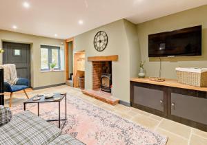 a living room with a fireplace and a clock on the wall at Grove Corner in Roughton