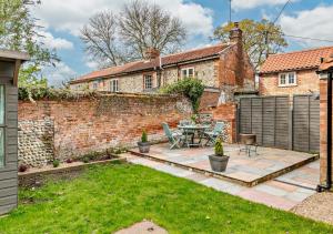 a garden with a patio and a brick wall at Grove Corner in Roughton