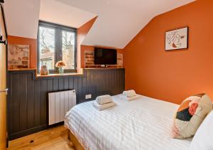 a bedroom with a bed with orange walls and a window at Grove Corner in Roughton