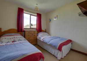 a bedroom with two beds and a window with red curtains at Happidays in Lessingham