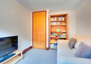 sala de estar con sofá y TV de pantalla plana en Haven Cottage, en South Walsham