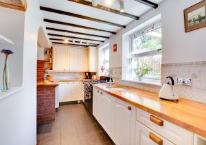 una cocina con armarios blancos y una ventana en Haven Cottage, en South Walsham