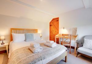 1 dormitorio con cama, silla y escritorio en Haven Cottage, en South Walsham