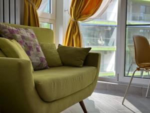 um sofá verde numa sala de estar com uma janela em Waves 54 em Mamaia Nord – Năvodari