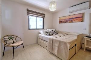 um quarto com uma cama, uma cadeira e uma janela em Center location, AC, swimming pool, and parking em Olhão