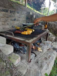 una persona está asando comida en una parrilla en Eco-Cabañas Altozano Nimaima, en Nimaima
