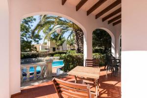 Un patio con mesa y sillas y una piscina. en Villa TRES JOANS, en Cala Galdana