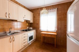 Una cocina con gabinetes blancos y un fregadero y una ventana. en Villa TRES JOANS, en Cala Galdana