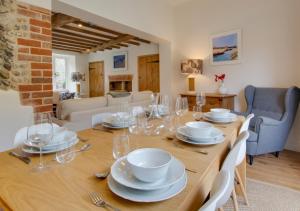 a dining room with a table with plates and glasses at Holly Cottage in Holt