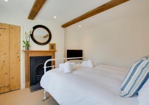 a bedroom with a white bed and a fireplace at Holly Cottage in Holt