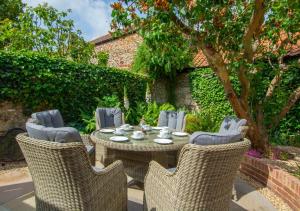 a wicker table and chairs in a garden at Holly Cottage in Holt