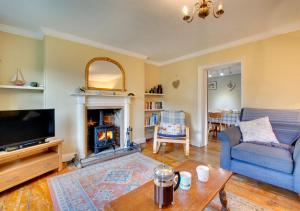 a living room with a blue couch and a fireplace at Holly Cottage in Cromer
