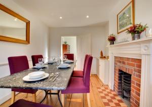a dining room with a table and a fireplace at Holly Cottage in Cromer