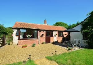 Ce cottage dispose d'une cour avec une table et des chaises. dans l'établissement Holly Cottage, à Banningham