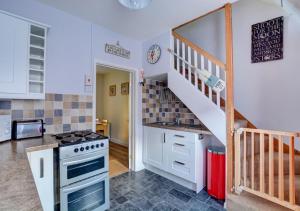 a kitchen with a stove top oven next to a staircase at Horseshoe Cottage in Cromer