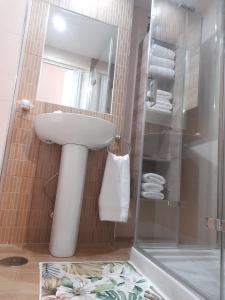 W łazience znajduje się biała umywalka i prysznic. w obiekcie Las Dunas w mieście El Puerto de Santa María