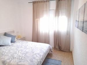 a bedroom with a white bed and a window at Las Dunas in El Puerto de Santa María