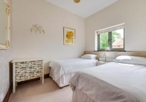 a bedroom with two beds and a window at Keepers Cottage in East Dereham