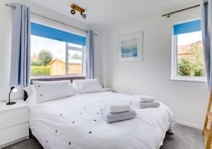 a bedroom with a white bed with two windows at Kenada in Docking