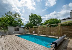 a swimming pool with a wooden deck and a fence at Knapton Hall Cottage in Knapton