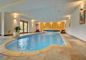 a large swimming pool in a room with a ceiling at Keepers Cottage in Panxworth