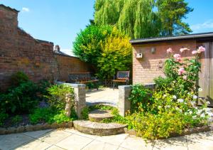 un jardín con bancos y flores y una pared de ladrillo en Laburnum House, en Kings Lynn