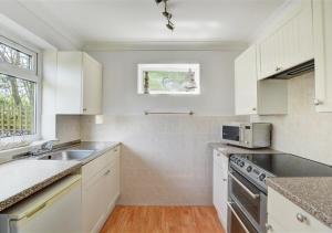 - une cuisine blanche avec évier et four micro-ondes dans l'établissement Lane End Cottage, à Snettisham