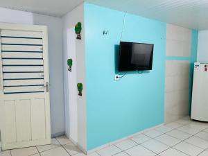 Habitación con TV en una pared con puerta en La casita Verde, en Beberibe