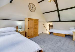 a bedroom with two beds and a clock on the wall at Lays Barn in Rockland Saint Peter