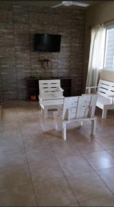 een kamer met 2 witte stoelen en een flatscreen-tv bij Casa con pileta in Santiago del Estero