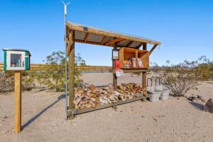 a wooden shelter with a pile of fire wood and buckets at JT Village Campground - Bunkhouse in Joshua Tree