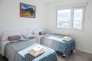 two beds in a room with a window at Gente del Sur - 25 de mayo in Ushuaia