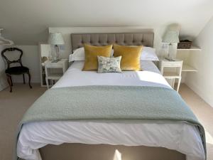 a bedroom with a large bed with yellow pillows at The Old Doctors Retreat- Near Soho Farmhouse in Sandford Saint Martin