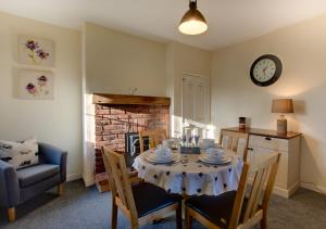 a dining room with a table with chairs and a clock at Lilac Cottage in Hindolveston
