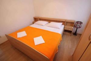 a bedroom with a bed with orange sheets and white pillows at One-Bedroom Apartment Crikvenica 14 in Dramalj