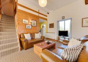 ein Wohnzimmer mit Ledersofas und einem TV in der Unterkunft Little Barn in Upton
